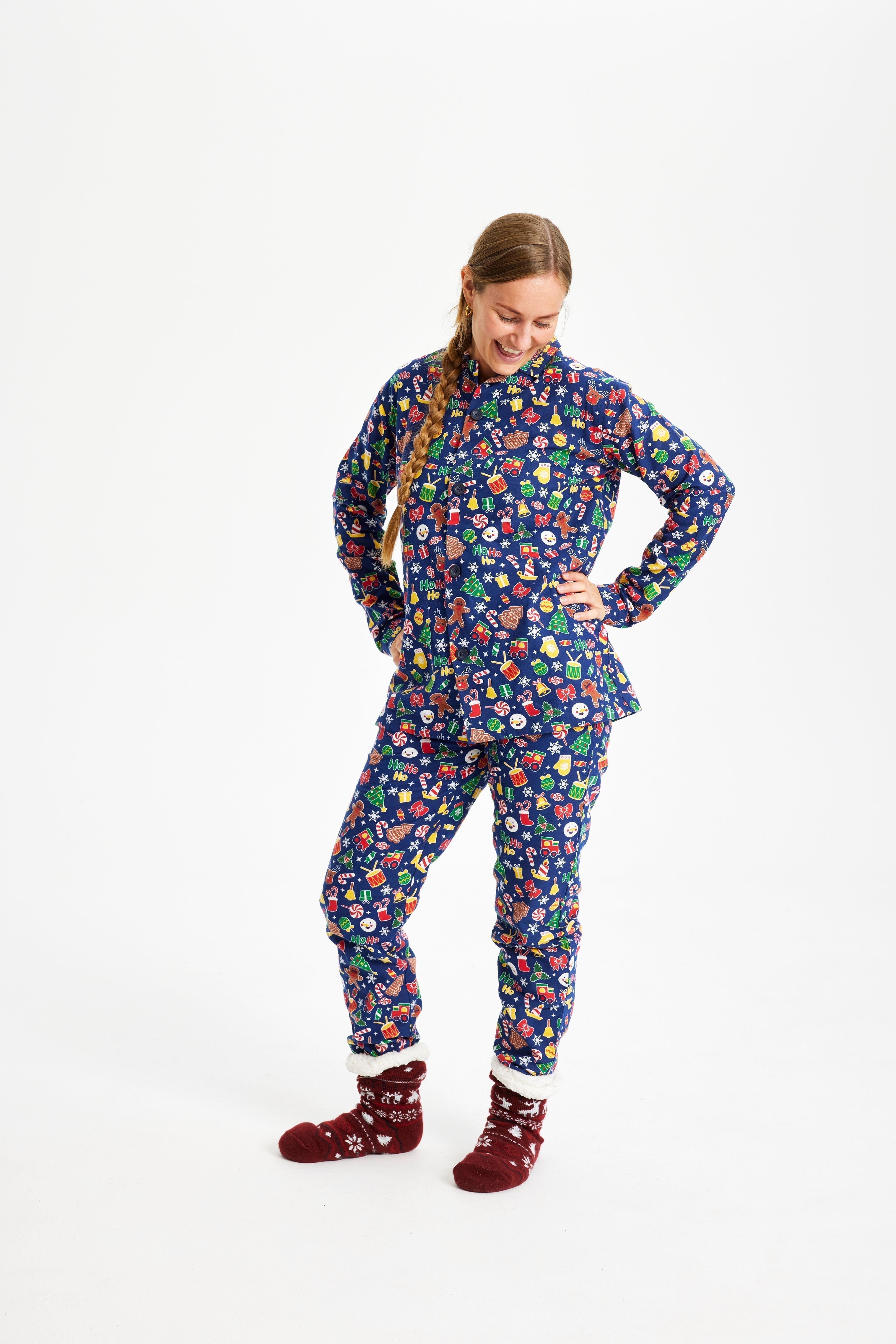 Une femme, les mains le long du corps, portant un pyjama de Noël bleu avec un imprimé de Noël.